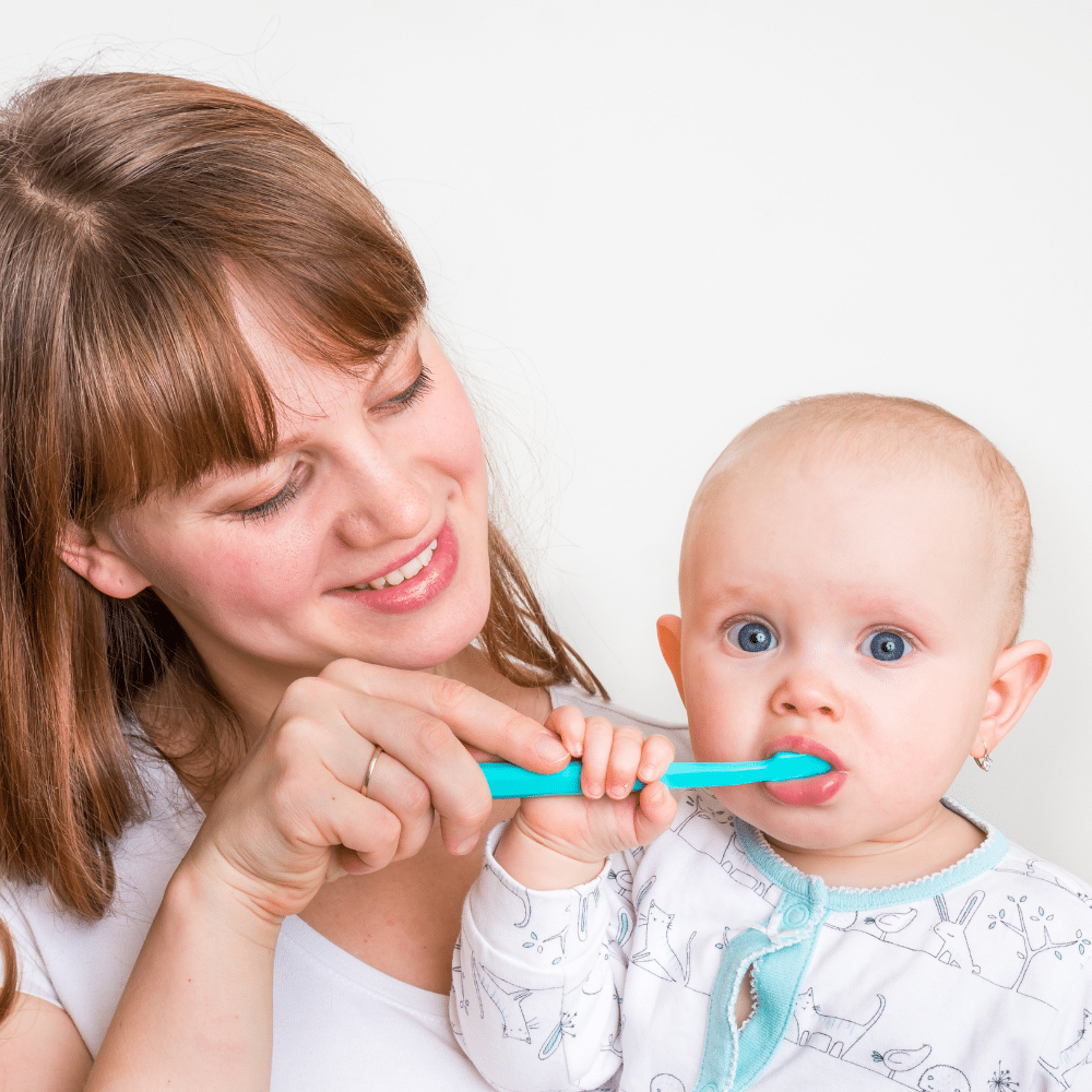 Mom helping baby brush teeth
